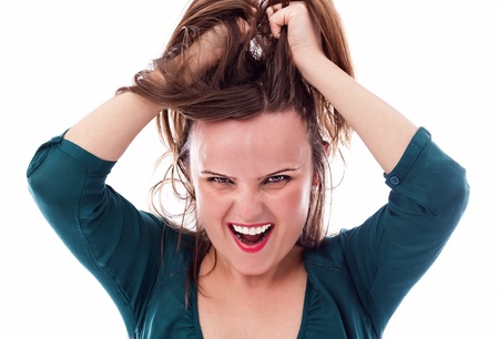 Closeup of an angry young woman pulling her hair isolated on white backgroundの写真素材