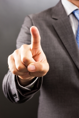 Businessman pressing an imaginary button against gray backgroundの写真素材