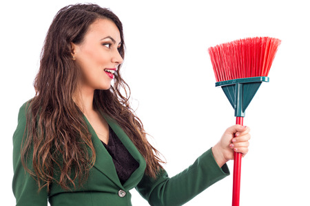 Happy young woman holding a broom against white background