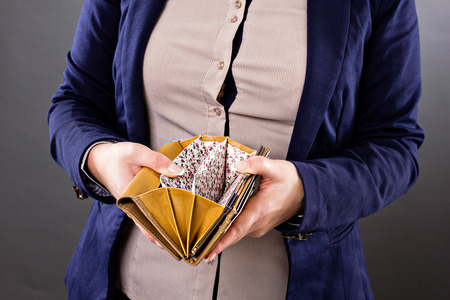 Closeup portrait of a businesswoman looking at an empty wallet over gray background
