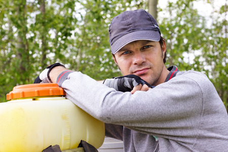 Portrait of a young farmer resting  in his orchard 