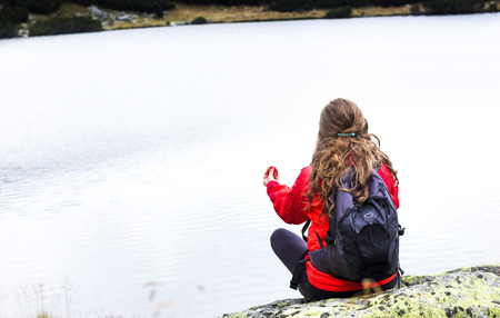 Young woman admiring the stillness of mountain  lake.Back viewの写真素材