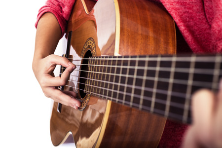 Closeup of girlÂ´s hands playing acoustic quitar isolated over white background
