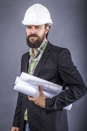 Closeup portrait of an angry engineer holding drawings over gray background