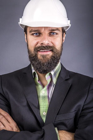 Closeup of young engineer with hardhat holding arms folded over gray backgroundの写真素材