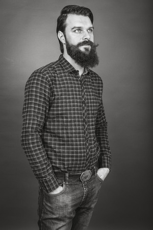 Studio shot of a handsome young man with retro look, beard and mustache, on grayの写真素材