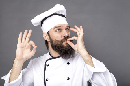 Studio shot of a bearded chef showing OK sign over gray backgroundの写真素材