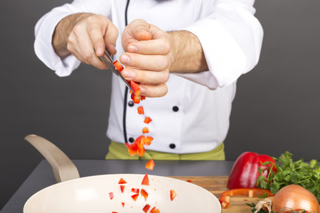 Closeup of chef hands putting chopped red pepper in a panの写真素材