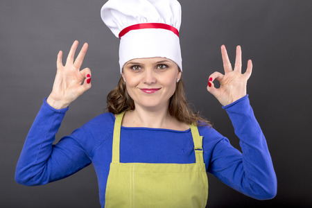 Happy young woman  making OK sign over gray backgroundの写真素材