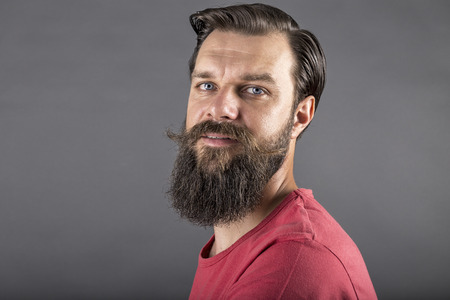 Portrait of a happy stylish man with beard and mustache over gray backgroundの写真素材