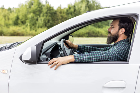 Side view of handsome young man driving his new car 