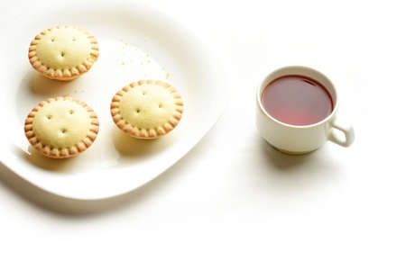 Shortcrust tartlets on a plate with a cup of black tea isolated on white backgroundの写真素材