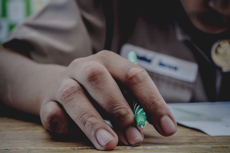Closeup to hand of student holding pen and taking exam in classroom with stress for education test.の写真素材