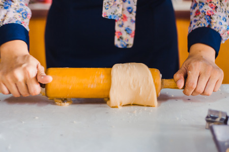 Teacher rolling out dough for 
demonstration to teach students how to make Singapore cookies.の写真素材