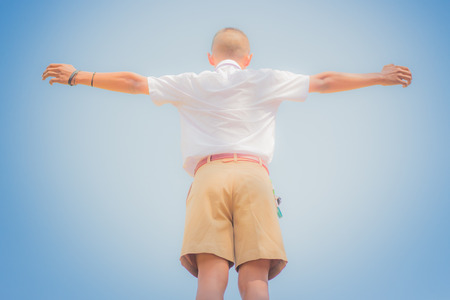 Student acting like a superhero on top of stepladder in school.の写真素材