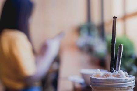 Cappuccino frappe cup on table with Blurred young girl waiting someone in coffeshop.の写真素材