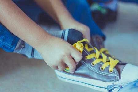 Kid is tying shoes laces before stage show in schoolの写真素材