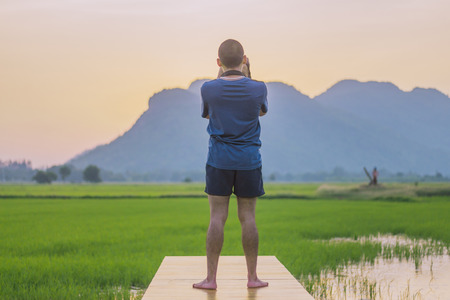 Young man practicing landscape photography before sunset at rice field.の写真素材
