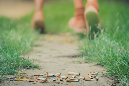 No Smoking concept. Smoking student is running away from his teacher in school. Selective focus on cigarette.の写真素材
