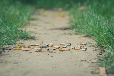 No Smoking concept. Smoking student is running away from his teacher in school. Selective focus on cigarette.の写真素材