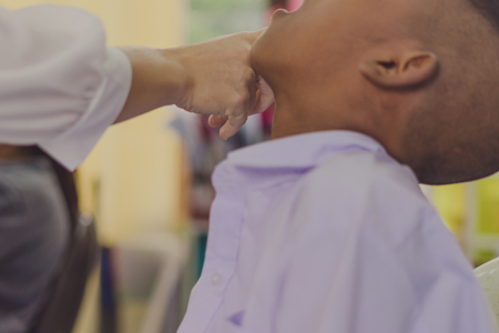 Doctor is checking the oral cavity of a student in school.の写真素材