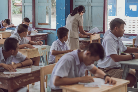 KANCHANABURI THAILAND - JULY 16 :  Unidentified Good teacher give midterm exam questions to students in the classroom on July 16,2018 at Watkrangthongratburana school in Kanchanaburi, Thailandのeditorial素材