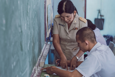 KANCHANABURI THAILAND - JULY 16 :  Unidentified Good teacher give midterm exam questions to students in the classroom on July 16,2018 at Watkrangthongratburana school in Kanchanaburi, Thailandのeditorial素材