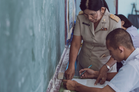 KANCHANABURI THAILAND - JULY 16 :  Unidentified Good teacher give midterm exam questions to students in the classroom on July 16,2018 at Watkrangthongratburana school in Kanchanaburi, Thailandのeditorial素材