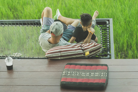 Dad and son relax on the balcony with a beautiful rice fields.のeditorial素材