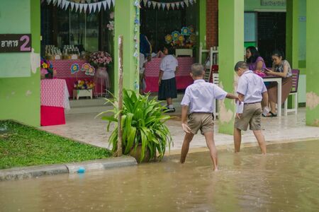 KANCHANABURI THAILAND - MARCH 9 :   Unidentified Students walk to the flood after rain to change class on March 9,2018 at Watkrangthongratburana school in Kanchanaburi, Thailandのeditorial素材