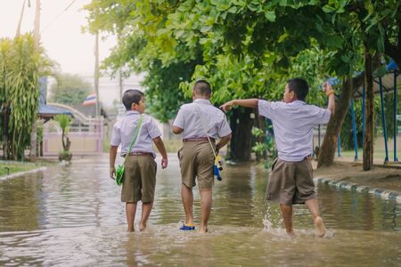 KANCHANABURI THAILAND - MARCH 9 :   Unidentified Students walk to the flood after rain to change class on March 9,2018 at Watkrangthongratburana school in Kanchanaburi, Thailandのeditorial素材