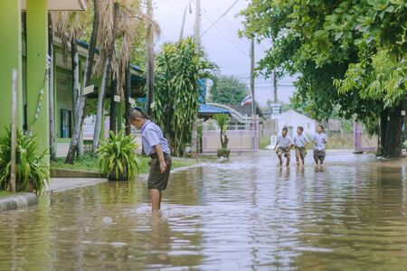 KANCHANABURI THAILAND - MARCH 9 :   Unidentified Students walk to the flood after rain to change class on March 9,2018 at Watkrangthongratburana school in Kanchanaburi, Thailandのeditorial素材