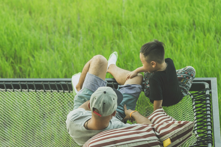 Dad and son relax on the balcony with a beautiful rice fields.の写真素材