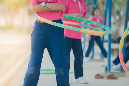 Female students doing exercise with a hula-hoop for a good healthy at school.の写真素材