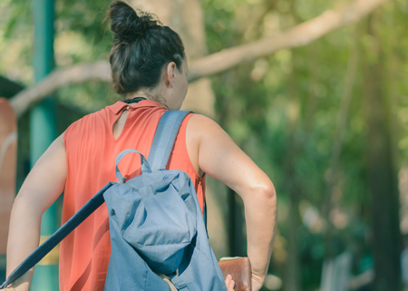 Back view of people walking on the hiking trail in the woods to Erawan waterfall in...