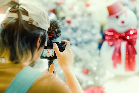 Photographer man take photo of decorated Christmas tree and a snowman.の写真素材