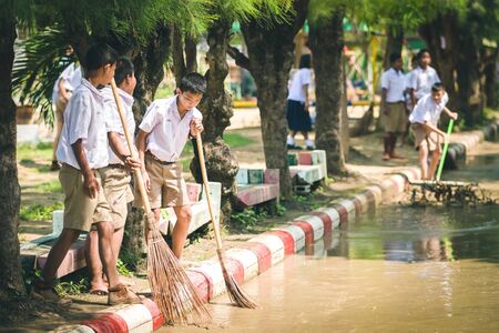 KANCHANABURI THAILAND - OCTOBER 8 : Unidentiffied Students help to clean the streets after heavy rain on October 8,2018 at Watkrangthongratburana school in Kanchanaburi, Thailandのeditorial素材