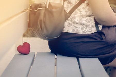 A woman sit and resting with little red heart shape pillow on chair in garden.の写真素材