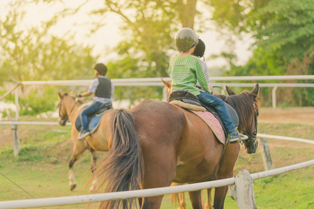 Kids learn to ride a horse near the river before sunset.の写真素材