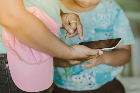 Mom and Her son using smartphone together in school.の写真素材