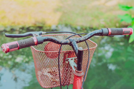 The old red bike hangs on a steel rail near the pool to decorate the garden.の写真素材