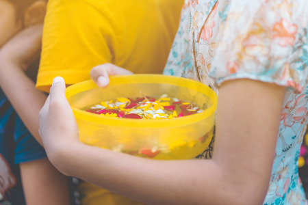 People are holding a bowl of water perfume with flower preparing to shower for the monks on Songkran day.(Thailand New Year)の写真素材