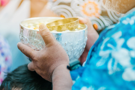 People are holding a bowl of water perfume with flower preparing to shower for the monksの写真素材