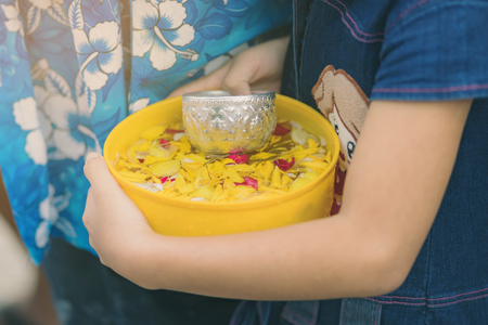 People are holding a bowl of water perfume with flower preparing to shower for the monks on Songkran...