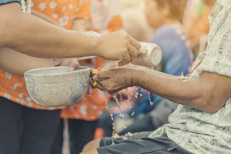 Thai people celebrate Songkran by pouring water and giving garlands to elder senior or respected grandparents and elder and asked for blessings for celebrate Songkran in new year water festivalの写真素材