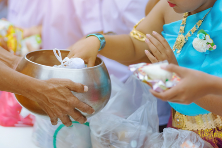 Teachers and students together make merit to give food offerings to a Buddhist monk on important religious days at school.の写真素材