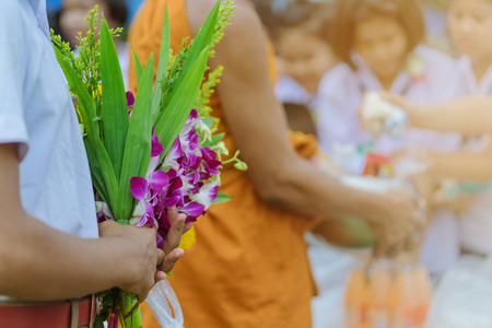 Teachers and students together make merit to give food offerings to a Buddhist monk on important...