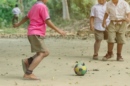 Student enjoy to play the old football with his friends on the ground in school.の写真素材