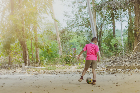Student enjoy to play the old football with his friends on the ground in school.の写真素材