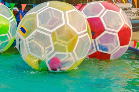Kid having fun in giant bubble ball on water in the swimming pool at the theme park in annual festival.の写真素材